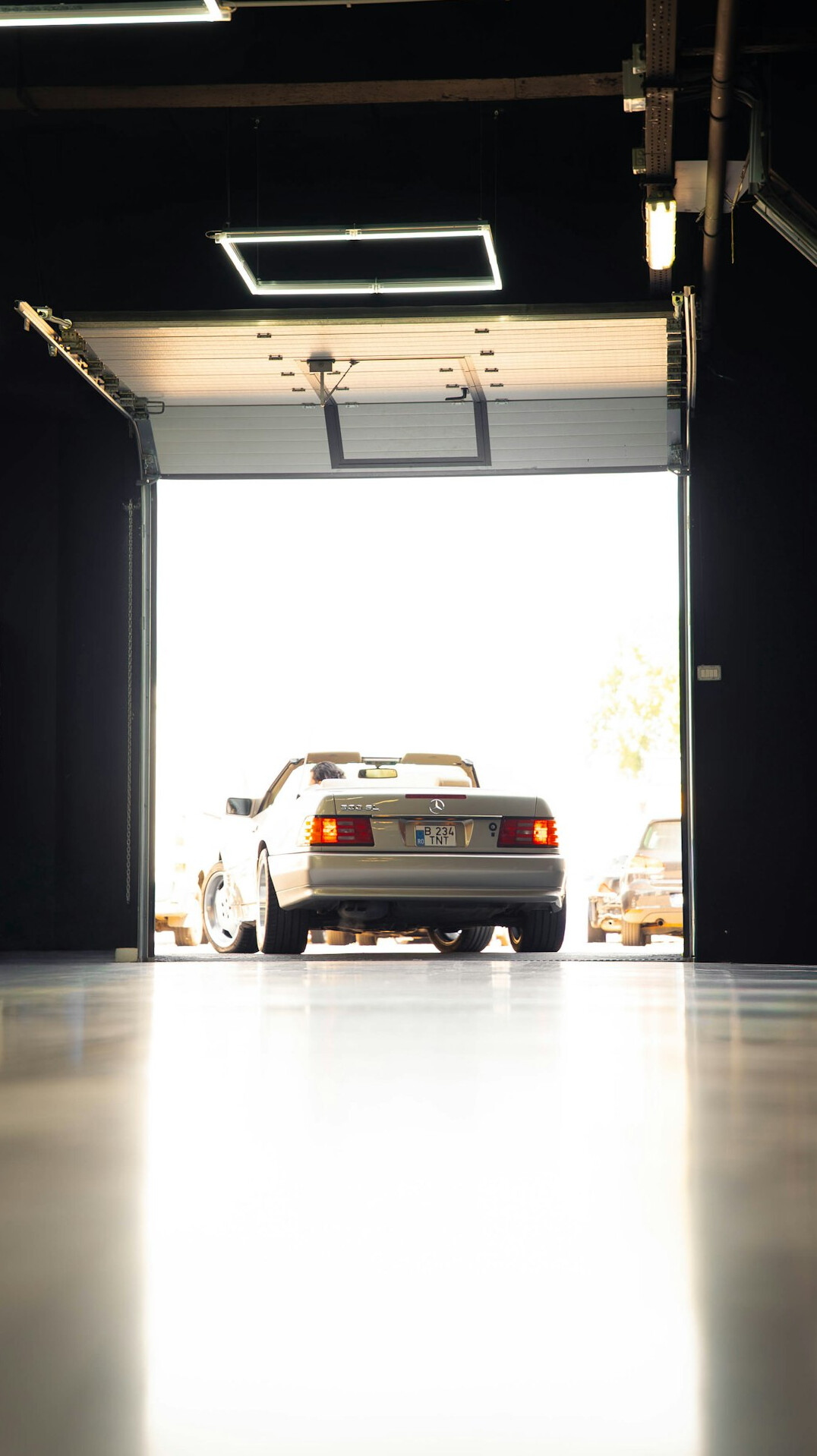 Dimly lit garage interior with classic automobile and vintage tools